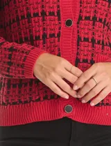 Cardigan tejido con diseño de cuadrille en contraste rojo y negro, escote redondo y cierre frontal con botones metálicos. Presenta bolsillos delanteros y terminaciones en rib en cuello, puños y ruedo.