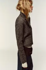 Chaqueta de punto con textura jaspeada, cuello solapa y manga larga. Presenta bolsillos delanteros de plastrón con solapa y cierre frontal con botones forrados a tono.