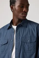 Camisa de hombre color azul marino, de manga larga, con cuello clásico y dos bolsillos frontales con solapa y botón.