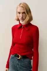 Top de manga larga confeccionado en tejido de punto acanalado. Presenta un diseño de ajuste ceñido con cuello alto y cierre frontal parcial.