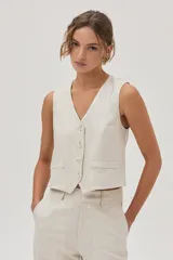 Chaleco sastrero color beige de lino y viscosa metalizado, con cuello en V y cierre con botones.