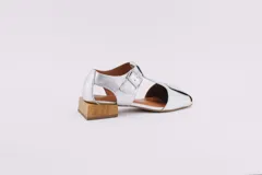 Sandalias de cuero color plateado con diseño de punta cerrada y talón descubierto. Presentan una tira con hebilla ajustable sobre el empeine y un taco cuadrado bajo con acabado de madera.