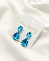 Par de caravanas colgantes con cristales facetados color celeste agua marina, engarzados en metal plateado. Cierre a presión.