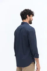 Camisa de gabardina azul marino con efecto stone wash, doble bolsillo frontal con solapa y botón, y fit regular.