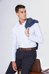 Camisa celeste lisa de tela Oxford, de manga larga, con logo bordado en el bolsillo, cuello con botones, tablón central en la espalda y botones personalizados.