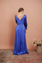 Vestido largo de satén color azul, con escote en V cruzado, mangas tres cuartos con detalles de lazos en los puños y falda larga con tajo frontal.