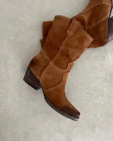 Bota corta estilo western confeccionada en cuero descarne color marrón, con taco cuadrado de madera y punta ligeramente afinada.