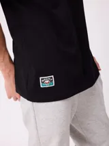 Remera negra de manga corta con gran estampado en la espalda de un paisaje natural montañoso, árboles, carpa y tipografía multicolor.