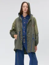 Campera tipo piloto con capucha, cierre frontal con botones y detalle de costuras en zigzag. Presenta cordones ajustables en la cintura y capucha, puños elásticos y logo bordado en el pecho.