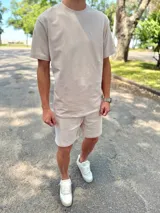 Conjunto deportivo beige compuesto por una remera de manga corta con cuello redondo y un short a juego con cordón ajustable.