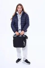 Bolso tipo shopper negro con diseño acolchado en forma de rombos. Cuenta con doble asa fija, correa regulable extraíble, bolsillos laterales y un bolsillo trasero con cierre. Incluye un pequeño aplique decorativo en el frente.