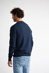 Sweater de tejido de punto en color verde oliva, con escote en V, manga larga y logo bordado en el pecho. Presenta un ajuste regular.