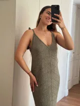 Vestido largo tejido en hilo de algodón y lurex color beige claro, con escote en V, tiras regulables en los hombros y tajos laterales. Presenta un patrón de puntos calados en forma de zigzag.