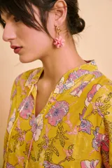 Aros colgantes dorados con un dije en forma de flor rosada.