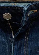 Jeans tiro medio de corte flare confeccionados en denim azul oscuro, con diseño de cinco bolsillos, trabillas para cinturón y bajo deshilachado.