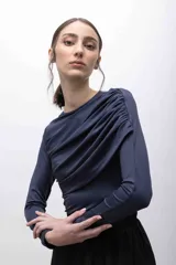 Top negro de mangas largas con frunces en el hombro izquierdo.