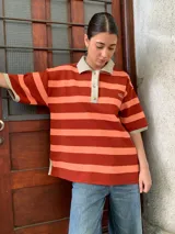 Remerón de algodón a rayas horizontales color naranja y salmón, con cuello tipo polo y mangas cortas.