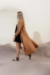 Tapado largo color camel, con cuello en V abierto, sin cierre y de corte fluido. Presenta mangas largas y bolsillos laterales.