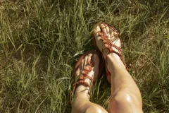 Sandalias bajas color hueso, con tira delantera con apliques de flores blancas y tira trasera con hebilla.