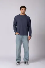 Buzo de cuello redondo y manga larga, confeccionado en tejido de punto acanalado de color negro. Presenta un diseño minimalista con un pequeño logo estampado en el pecho y un corte relajado.