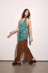 Vestido largo amarillo con escote halter y detalle de volados en el cuello. Presenta un diseño superpuesto con una capa superior estampada a cuadros multicolor con nudo lateral en la cintura y una falda fluida lisa con abertura lateral.