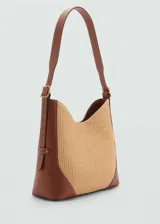 Bolso tipo hobo de rafia color beige, con detalles en cuero marrón. Tiene asa de hombro ajustable, cierre con botón magnético y bolsillo interior.