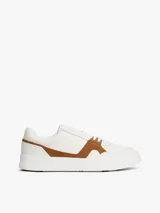 Zapatillas de corte bajo Tommy Hilfiger con diseño inspirado en el tenis, confeccionadas en piel napa blanca con paneles laterales de gamuza en color marrón. Presentan cierre con cordones, suela de goma y detalles de logo en bajo relieve.