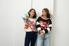 Buzo de tejido de punto con diseño estampado de flores abstractas y mangas a rayas. Presenta cuello redondo y corte holgado.