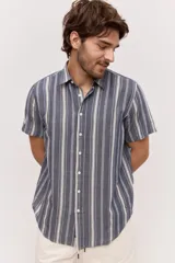 Camisa de manga corta color azul con diseño a rayas verticales, cuello clásico y cierre frontal de botones.