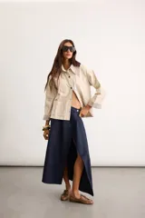 Sobrecamisa de algodón color beige, de corte holgado, con bolsillos frontales aplicados, cuello camisero y puños en contraste con estampado de cuadros en tonos verde oscuro. Cuenta con cierre frontal de botones metálicos.