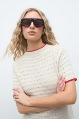 Remera de punto color crudo con detalles en rojo en el cuello y las mangas, manga corta y diseño texturizado.