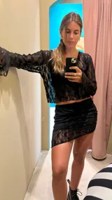 Blusa corta de encaje negro con mangas largas acampanadas.