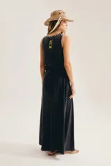 Maxi vestido negro sin mangas, con cuello redondo y silueta suelta que se abre en A hacia el ruedo. Confeccionado en 100% algodón, incluye aplique trasero en forma de X.