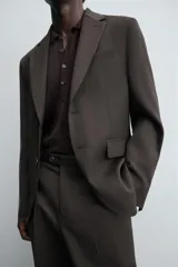 Blazer de corte regular confeccionada en tejido de lana. Presenta cuello con solapas de muesca, cierre frontal de un botón y manga larga con puños abotonados. Cuenta con bolsillos de vivo en el pecho, bolsillos con solapa en la cadera y aberturas en la parte posterior.