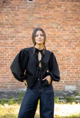 Blusa de lino color negro con mangas abullonadas y cierre frontal mediante lazos ajustables. Presenta un diseño de silueta relajada y escote con abertura.