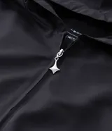 Campera con capucha de estilo deportivo, confeccionada en poliéster con diseño de paneles en colores negro, blanco y bordó. Presenta cierre frontal con cremallera, puños elásticos y bolsillos laterales.