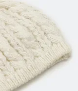 Gorro de punto color crema con diseño de trenzas.