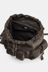 Mochila marrón con múltiples bolsillos con cierre magnético, correas con hebillas, bolsillo interior con cremallera metálica y cierre mediante frunce y solapa con cierre imantado.