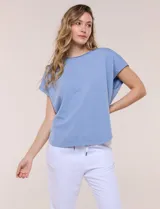 Remera de silueta amplia y relajada confeccionada en algodón y poliéster, de color verde, con escote a la base y mangas cortas de hombro caído. Presenta dobladillo enrollado y ruedo curvo.