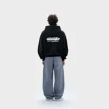 Hoodie negro de corte holgado con capucha y estampa gráfica blanca en la espalda con estilo tipográfico urbano.