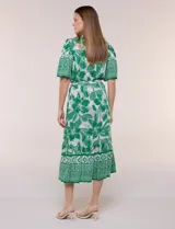 Vestido midi de estilo bohemio en color verde y blanco, con estampa floral, escote en V, cierre frontal con botones, mangas cortas amplias, cintura ajustable con lazo y volado en el bajo.