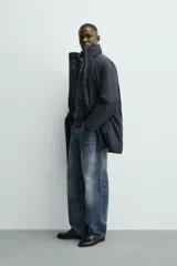 Parka acolchada impermeable color gris oscuro, de corte regular fit, con cuello doble subido, bolsillos de vivo en la cadera y cierre frontal con cremallera oculta por solapa con botones a presión.