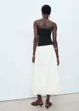 Vestido midi de diseño combinado con cuerpo tipo strapless en color negro y falda estilo globo en color blanco. Presenta un bajo abullonado y forro interior de algodón.