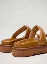 Sandalias de cuero vacuno color marrón con acabado brillante, diseño de dos tiras anchas acolchadas y plataforma baja.