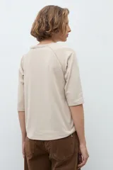 Remera de manga tres cuartos con diseño raglán y detalle de costura decorativa en los hombros. Presenta cuello redondo y un corte clásico.