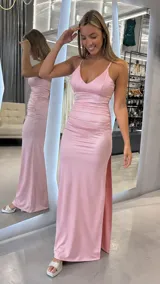 Vestido largo de satén rosa con escote en V, tirantes finos cruzados en la espalda, fruncidos en el talle y tajo lateral en la falda.