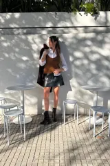 Minifalda negra de cuero sintético con corte campana y costuras decorativas en hilo blanco.