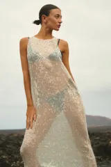 Vestido largo sin mangas, de corte amplio y confeccionado en lentejuelas color plateado.