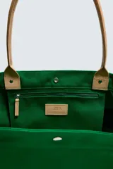 Bolso tipo shopper de tejido de algodón color verde, con asas de mano en piel color beige y cierre superior mediante botones a presión. Cuenta con compartimento principal amplio y bolsillos interiores.