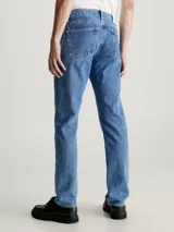 Jeans de denim rígido azul medio con lavado a la piedra, talle medio a bajo y pierna recta larga. Presenta diseño de cinco bolsillos y bragueta con cremallera.